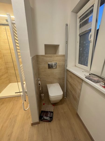 Závěsné WC s béžovým obkladem a nikou